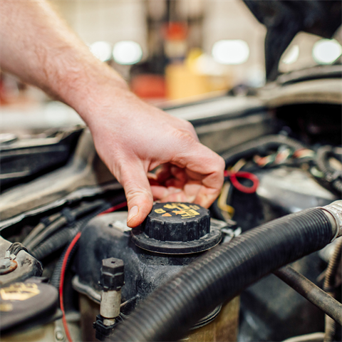 Photograph of a person tightening a cap on a vehicle's engine