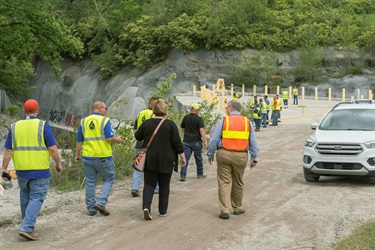 People walking down a steep dirt hill toward a large stormwater tunnel