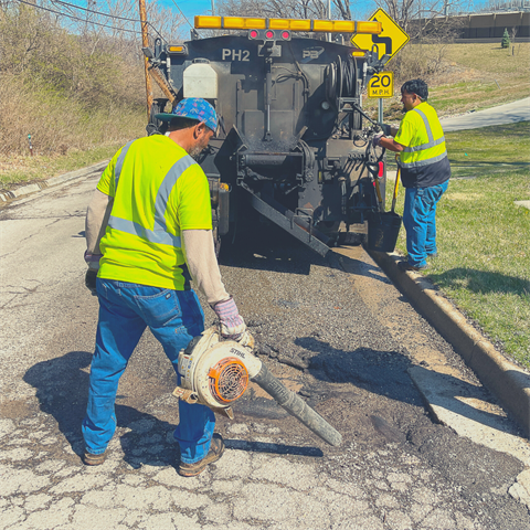 Public Works team clearing debris away from a pothole that will be patched