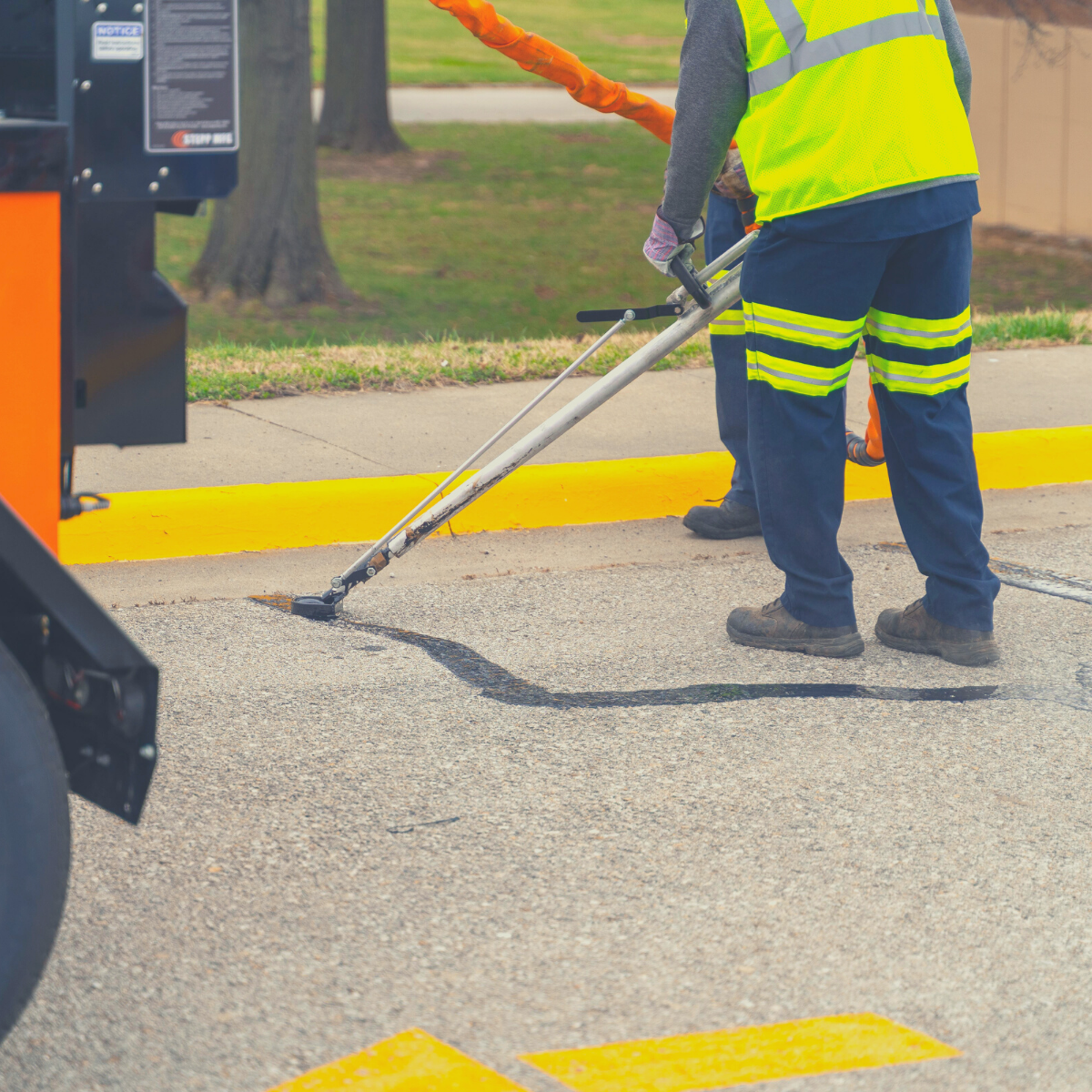 Photograph of a crew using a mobile crack sealer to fill gaps in street pavement