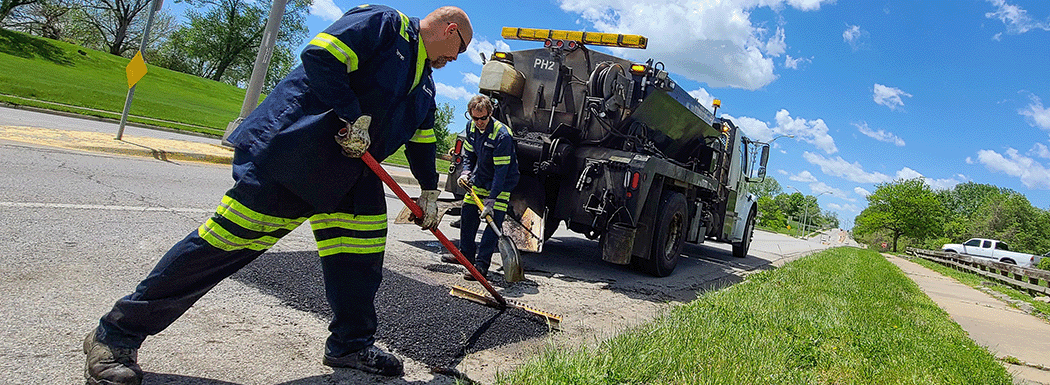 A crew of people working to patch a pothole on a street