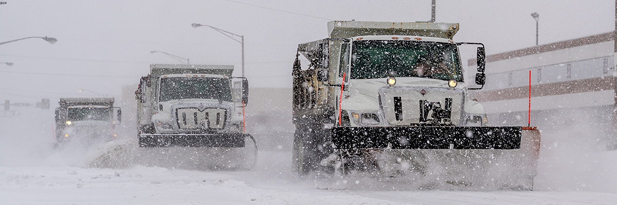 Photograph of snow trucks plowing snow during a winter storm
