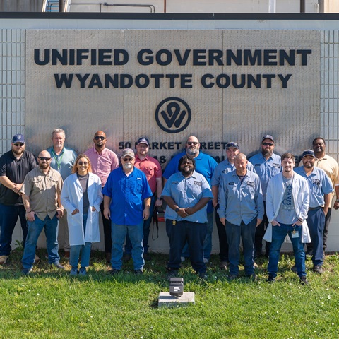 Photograph of Kaw Point Treatment plant team members posing in front of their building sign